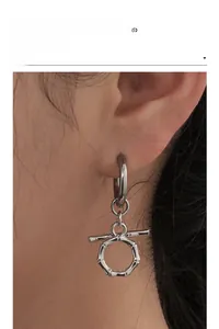Detailed close-up of a silver-tone bamboo texture earring with a T-bar pendant on a model
