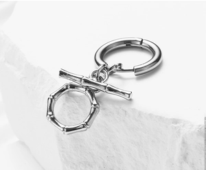 Macro shot of silver stainless steel hoop earrings with bamboo joint charms on stone