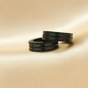 Schwarze Titanstahl-Creolen mit gerilltem Design auf Champagner-Seidenhintergrund