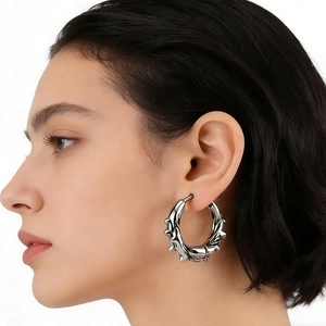 Punk style silver stainless steel hoop earring with thorny texture worn by a model