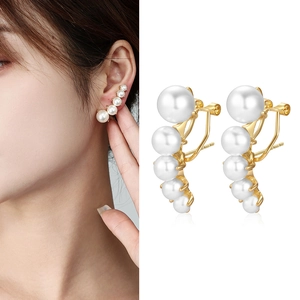 Boucle d'oreille manchette dorée avec perles blanches sur mannequin et fond blanc