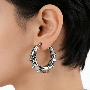 Macro detail of silver stainless steel hoop earring with punk style thorn textures