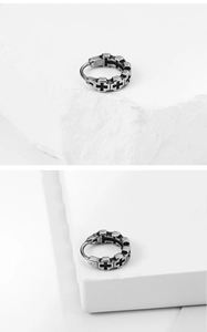 Macro shot of vintage titanium steel hoop earring with embossed cross patterns