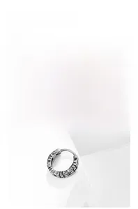 Detail of vintage silver heart hoop earring with engraved floral patterns and relief texture