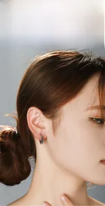 Detail of vintage gothic cross earrings with embossed texture on a model's ear