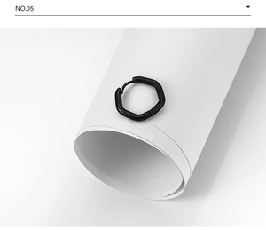 Vue détaillée d'une boucle d'oreille hexagonale noire mate en titane sur fond blanc épuré