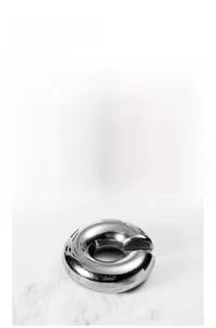 Detailed view of polished silver steel C-shape ear cuff on white textured background