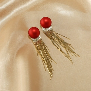 Nahaufnahme der roten matten Kugelohrringe mit eleganten goldenen Kettenquasten