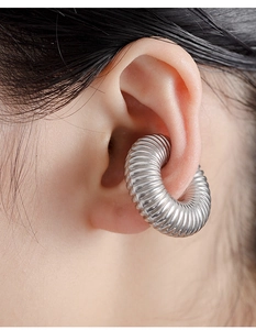 Close-up of a chunky silver stainless steel hoop earring with textured spiral pattern