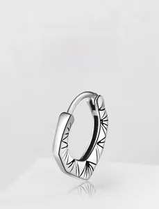 Macro view of silver steel hoop earring with black geometric radial line patterns