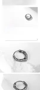 Detail of vintage silver titanium steel earring with radial pattern on marble surface