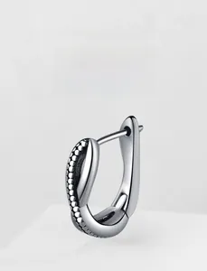 Macro detail of industrial retro cross steel earring with textured caviar finish