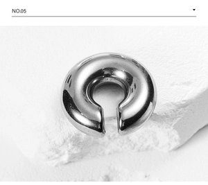 Detailed view of polished silver steel C-shaped hoop earring on white stone surface