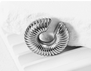 Macro detail of silver stainless steel ear cuff with industrial spiral textured finish