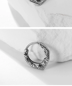 Detail of retro titanium steel hoop earring with hexagonal design and textured finish