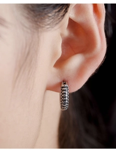 Close-up of vintage titanium steel hoop earring with detailed scale texture on model