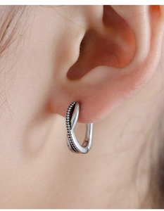 Macro view of vintage silver twisted rope earring with fine dot texture on skin