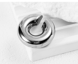 Close-up of a chunky silver stainless steel ear cuff with a polished mirror finish on white steps