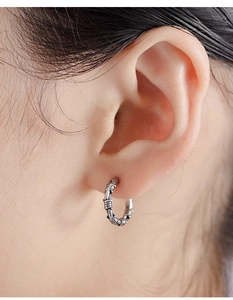 Close-up of vintage punk earrings with barbed wire texture on a human ear
