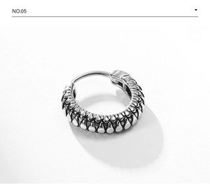 Macro detail of vintage punk huggie earring with textured scale pattern in aged silver