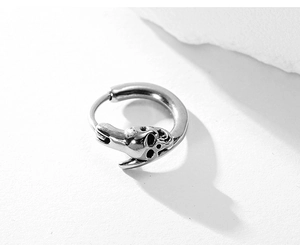 Close-up of a polished silver stainless steel hoop earring with a 3D skull pendant