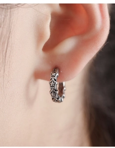 Macro shot of vintage silver star earrings with detailed engraving on earlobe