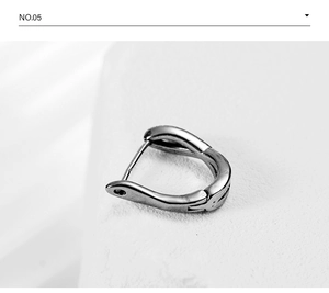 Macro detail of silver cross huggie hoop earring with vintage twisted metal texture