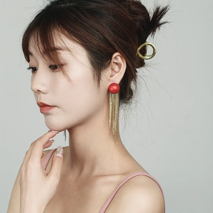 Detailansicht der roten Ohrstecker mit goldenen Kettenquasten am Modelprofil