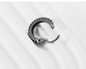 Detailed macro view of vintage silver steel hoop earring with textured industrial pattern
