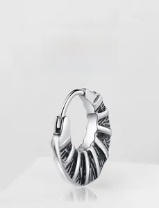 Macro detail of retro industrial textured steel hoop earring with black vintage finish