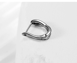 Macro shot of silver huggie earrings with a sleek hinged closure on a textured stone
