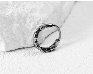 Detail of vintage oxidized silver hoop earring with industrial winding texture on rock