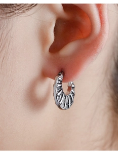 Macro shot of retro silver hoop earring with radial texture and punk style finish