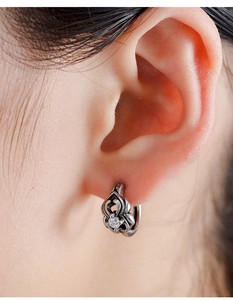 Macro shot of vintage cross earring with engraved patterns and a central clear zircon