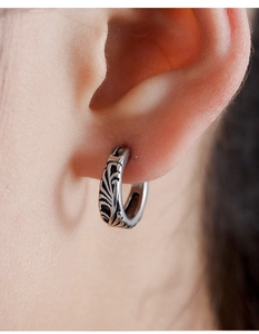 Macro shot of vintage silver steel hoop earring with engraved tribal vine patterns