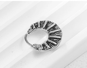 Macro shot of retro silver cross earrings with radial engraved vintage metal texture