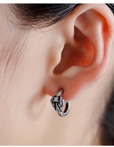 Detail of vintage silver hoop earring with embossed patterns and small clear gemstone