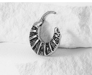 Macro shot of vintage croissant hoop earring with radial grooves on textured stone base