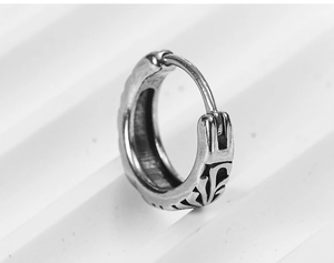Macro view of vintage silver hoop earring featuring gothic cross engravings and rustic finish