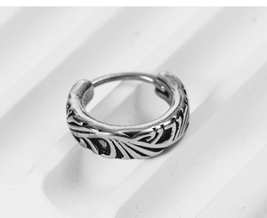 Macro shot of vintage silver earrings featuring intricate leaf relief and punk style texture