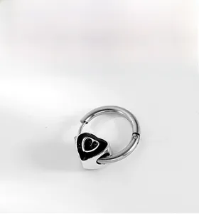 Close-up of vintage silver hoop earring with black enamel heart charm and cutout detail