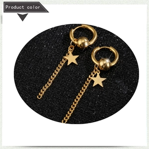 Detailaufnahme goldener Ohrringe mit Sternanhänger und Ketten auf schwarzem Glitzerhintergrund