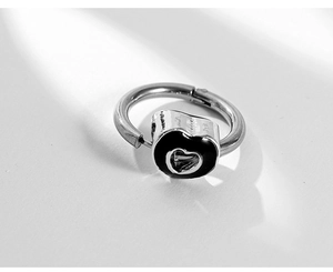 Macro detail of silver hoop earring featuring a black enamel heart with hollow center