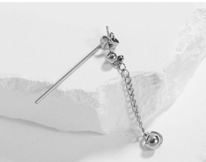 Macro shot of a silver geometric industrial drop earring with chain on a stone background