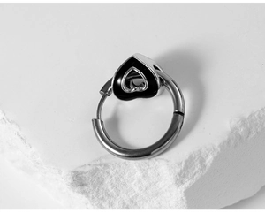 Close-up of silver hoop earring featuring a black enamel hollow heart pendant on stone