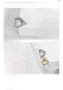 Macro view of mirror polished titanium steel heart hoop earrings in gold and silver finish