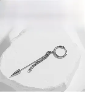 Macro view of polished silver steel cross earring with chain on a textured stone surface