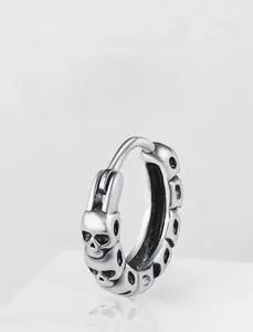 Detail view of retro silver huggie hoop earrings featuring continuous skull carving design