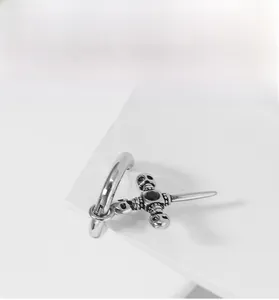 Detail of silver gothic cross earring with skull accents and a centered black gemstone