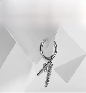 Detail view of steel cross hoop earring with hanging chain on artistic white background